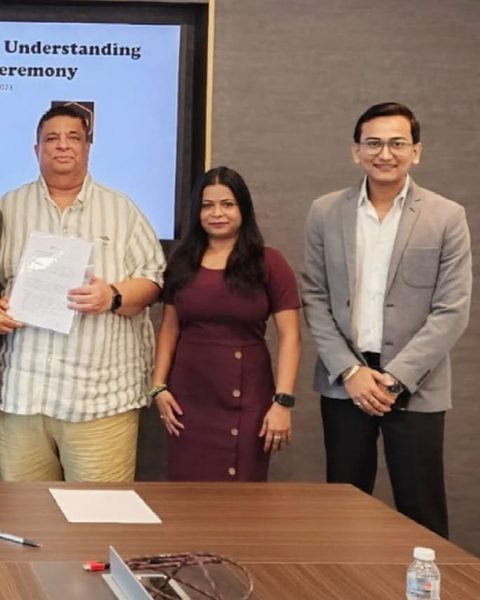 Snehaashish Pathakk, in a grey blazer and glasses, at an MoU signing ceremony in Malaysia, August 2023, beside two other attendees as a document is presented.